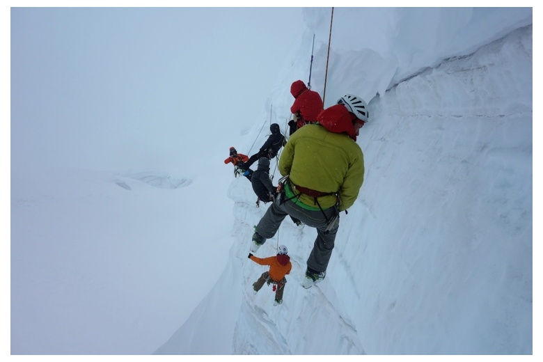 climbers abseiling on an icy and snowy wall